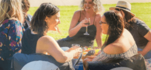 Group of Australian women goes to Moonlight Cinema enjoying their drinks while sitting in a black bean bag sofa chair