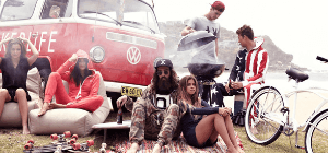 Group of friends having a cookout beside red van while sitting on beige bean bag sofa chairs