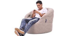 Pierced man using his phone sitting in a gold class butterfly sofa bean bag