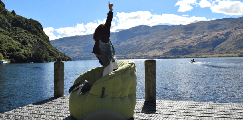 Australian girl enjoying the lake view while kneeling on the green bean bag sofa chair 