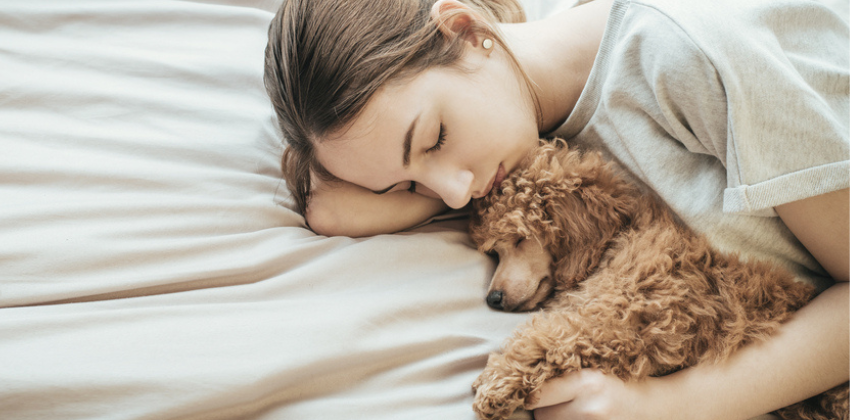 woman sleeping and cuddling with her dog