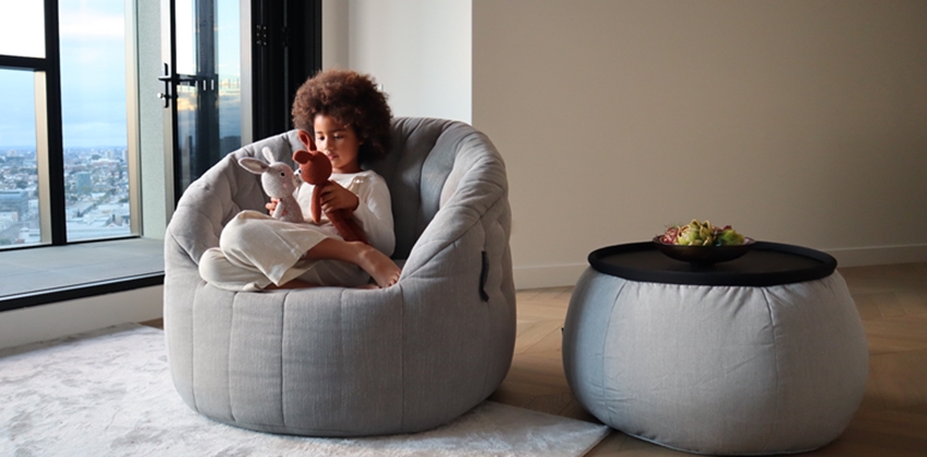 large grey linen luxury kids bean bag by ambient lounge with a girl playing with her stuffed animal toy